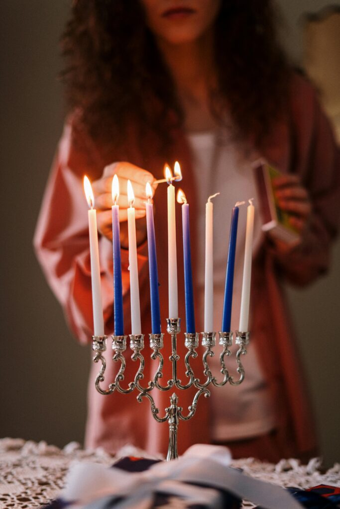 A woman lighting a menorah in celebration of Hanukkah, capturing the festival's warm essence.
